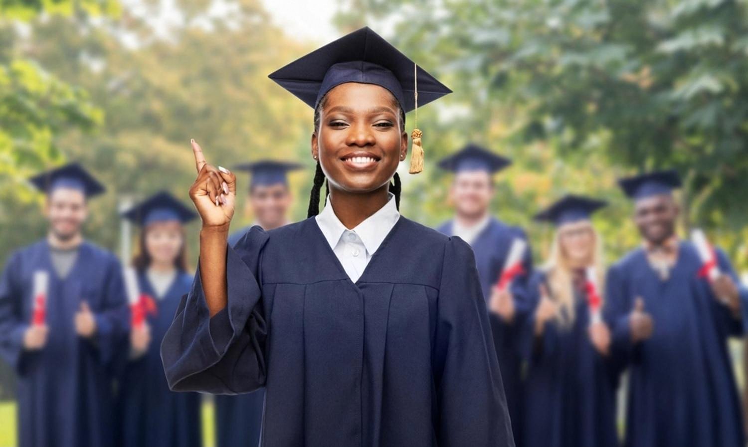 Smiling graduate in cap and gown with fellow graduates behind her, illustrating university pathways after Indian school in Ajman